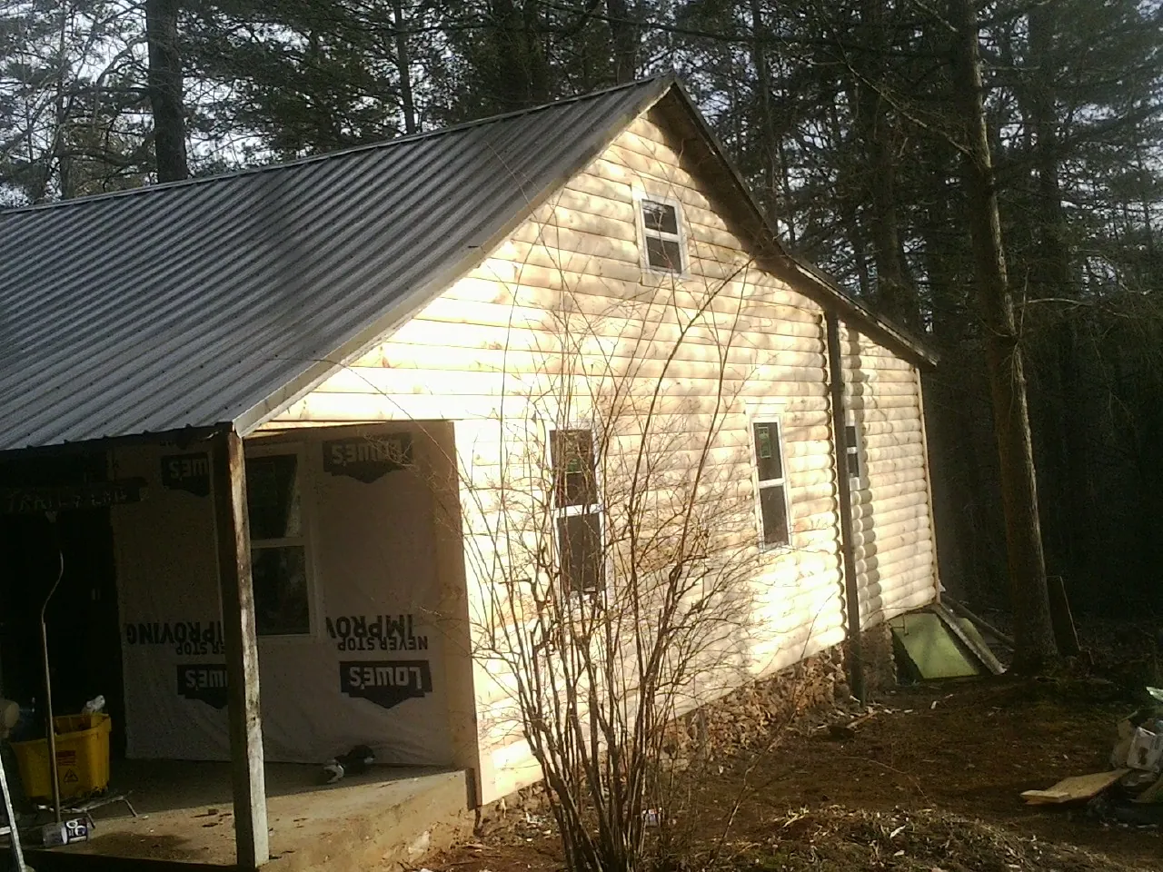 Log siding gable end under a dark metal roof edge in Hellier