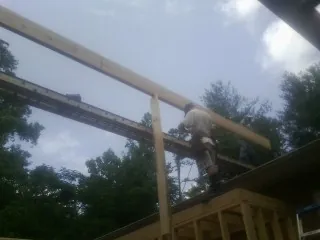 Carpenter setting a ridge beam over a new addition frame — Ice Dam Removal by Roofing Brothers in Hellier