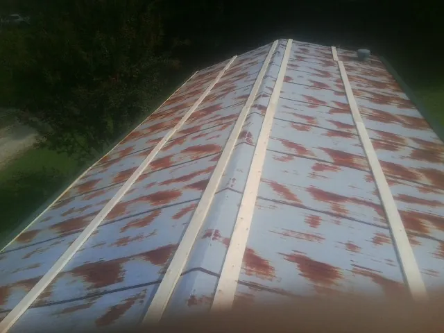 Rusted metal roof panels with new wood purlins before replacement — Storm Damage Roof Repair in Hellier by Roofing Brothers