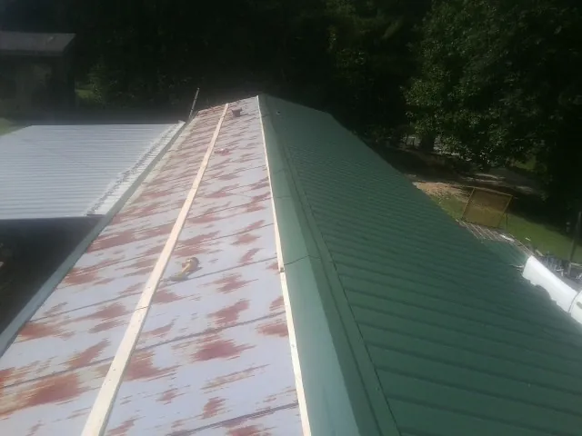 Old rusted panels beside newly installed green metal roofing — Wind Damage Roof Repair by Roofing Brothers in Hellier