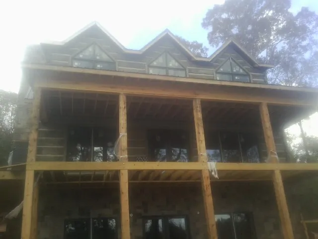 Dormers and porch framing on a large log home under construction — Roof Coating work by our crew in Hellier